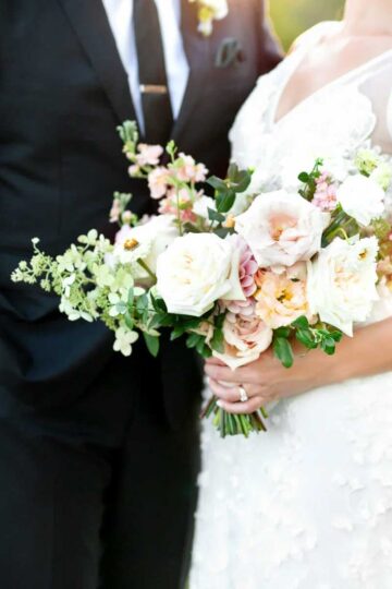 bride and groom standing together with bride holding floral bouquet