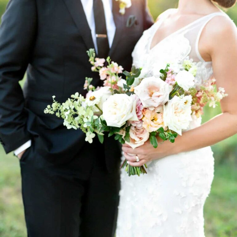 bride and groom standing together with bride holding floral bouquet