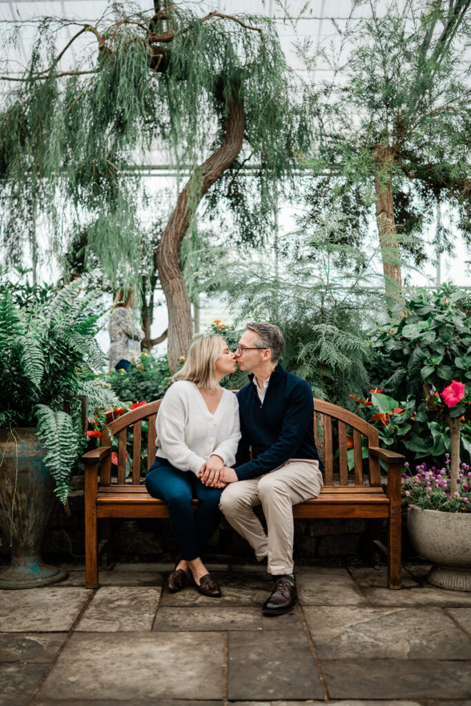 couple sitting on a bench in botanical garden greenhouse