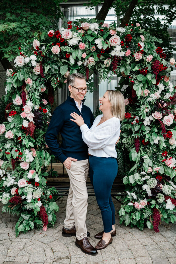 couple standing under floral arch