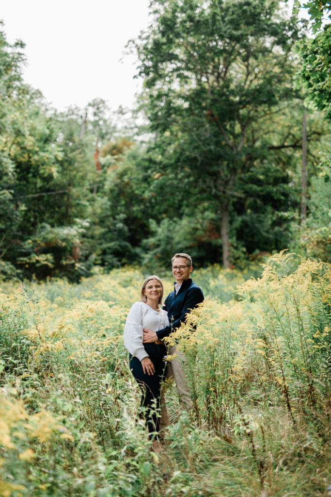 couple taking engagement photos standing in field