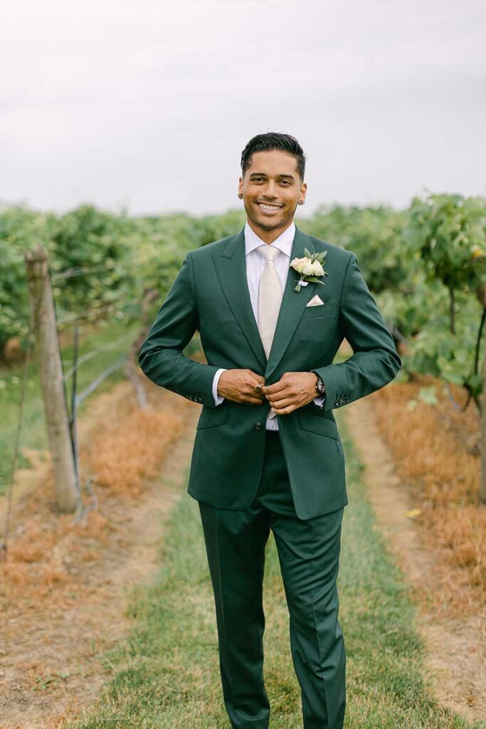groom wearing green suit in vineyard