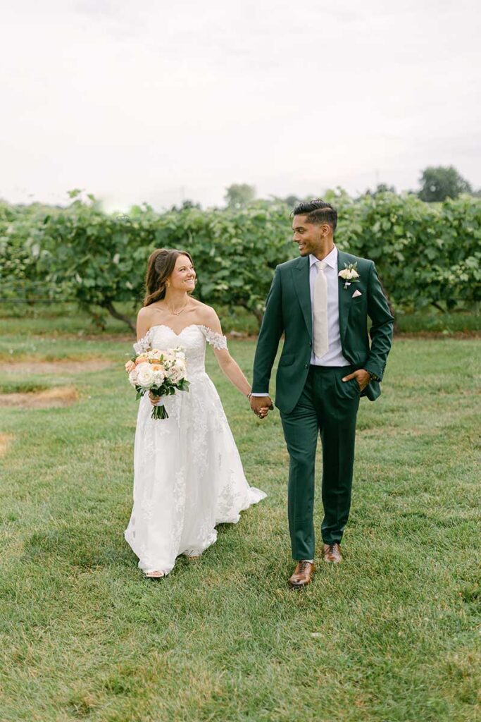 bride and groom walking through vineyard