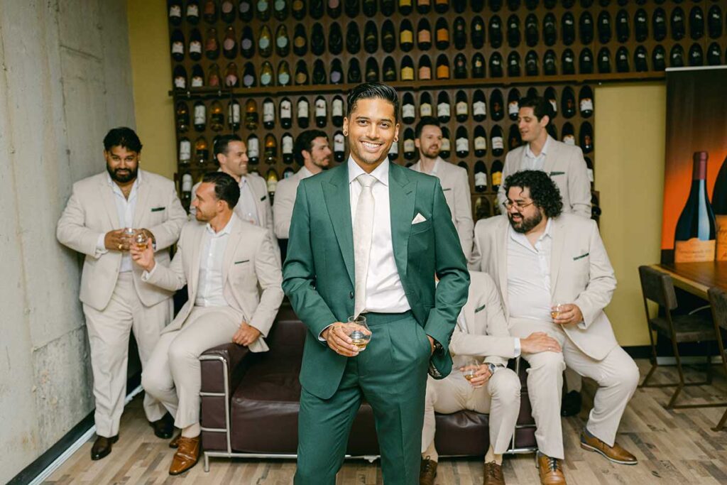 groom holding cocktail glass with groomsmen in background